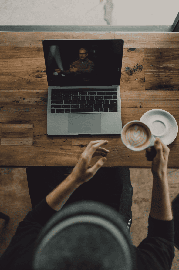 Lebensstil eines Kaffeetrinkers mit Laptop an einem Holztisch, urbaner Arbeitsbereich, gemütliches Kaffee-Umfeld, moderne Arbeitskultur, Fokus auf Produktivität und Wohlbefinden, ideal für kreative Berufsgruppen und Freiberufler.