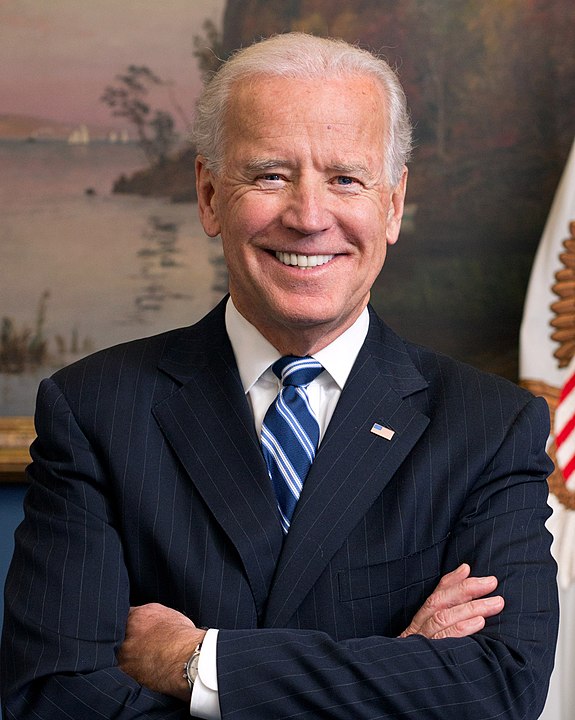 Der US-Präsident Joe Biden in einem Anzug mit US-Flaggenabzeichen, lächelnd vor einem Gemälde mit Flusslandschaft, symbolisiert amerikanische Führung und politische Ämter.