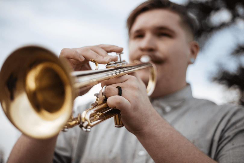 Mitmachmusiker spielt Trompete, Musik, Blasinstrument, outdoor, junge Frau, kreative Unterhaltung, musikalische Aktivitäten, Hobby, Sommer, Natur, Festival, Freude, Musiker, Gemeinschaft, Klang, Event, Instrumentenspiel.