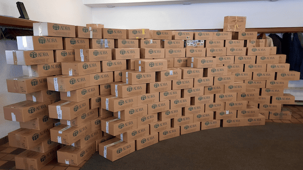 1. Stapel unzähliger brauner Versandkartons mit ADRA Logo für Versand und Logistik.