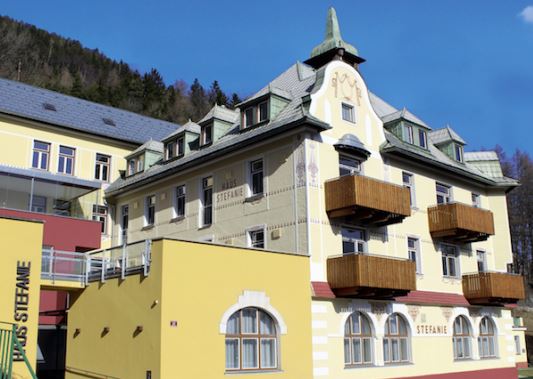 Historisches Hotel im alpinen Stil inmitten der Berge, mit traditionellen Balkonen und charmantem Ambiente – ideal für Erholung und Winterurlaub in den österreichischen Alpen.