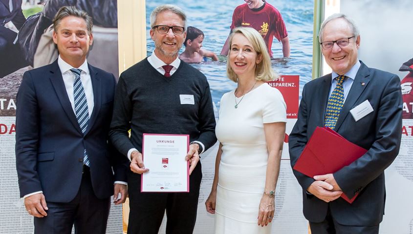 Erwachsene bei einer feierlichen Zeremonie, Auszeichnung bekommen, formelle Kleidung, Unternehmensveranstaltung, Freude, Ehrung, Jubiläum, beruflicher Erfolg, Team, Feierlichkeit, Advent-Verlag, professionelle Atmosphäre, Erfolgskonferenz, Mitarbeiterehrung, Verlagsbranche.