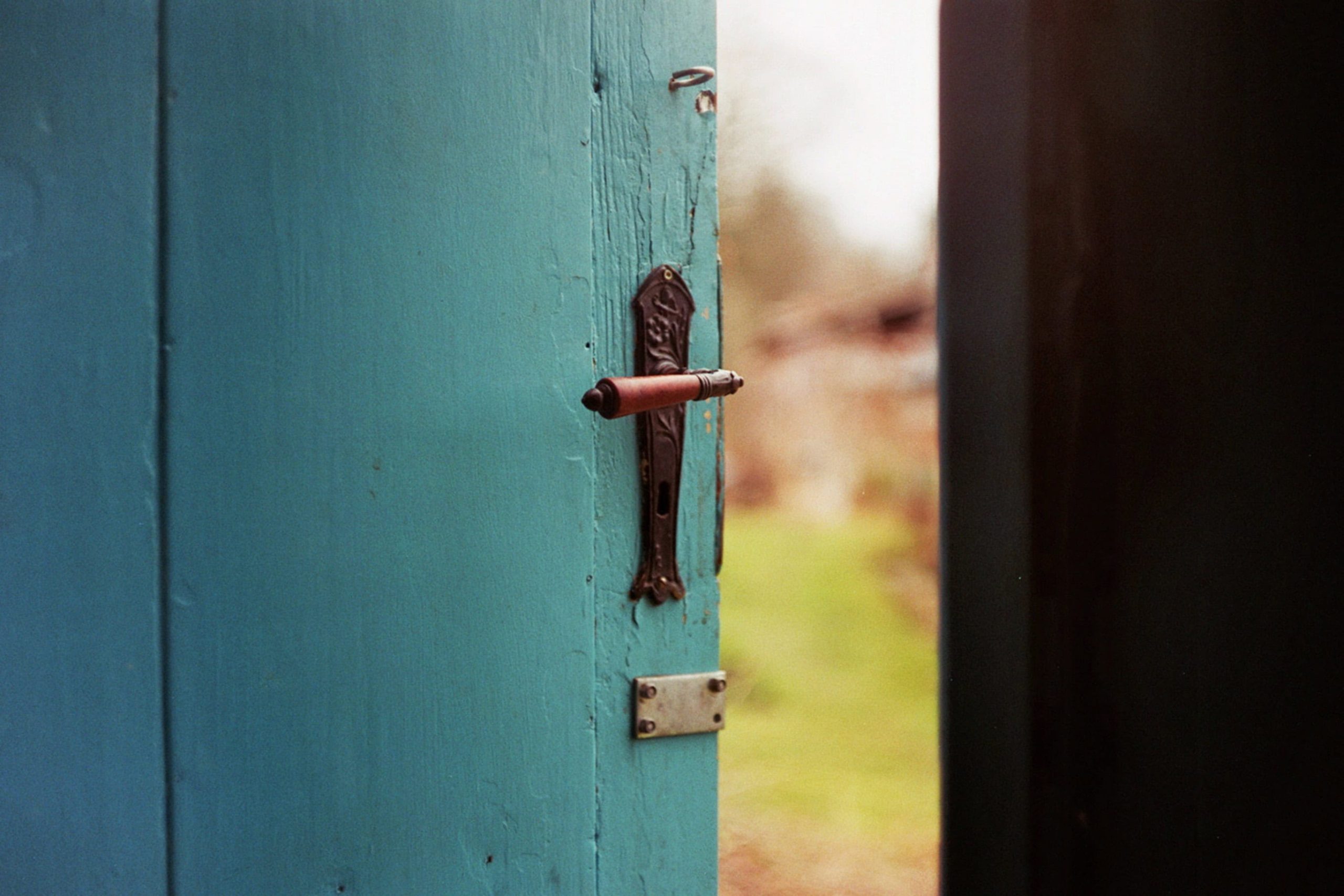 Türgriff an einer grünen Holztür, Einladung zum Eintreten, Hausöffnung, ländlich, nostalgisch, handgefertigt, rustikal, einladend, Türschloss, Haustür, ländliches Zuhause, Türöffnung, nostalgischer Charme, ländliche Architektur, Advent-Verlag, Blick nach draußen.