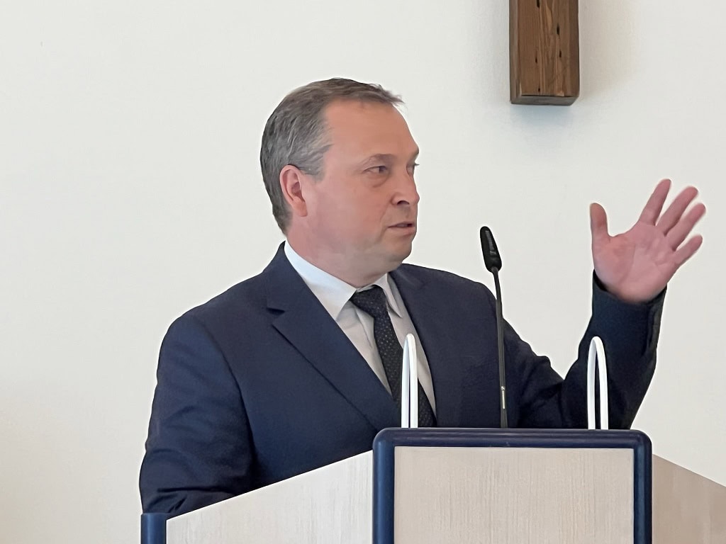 1. Moderner Mann in Anzug hält Vortrag, spricht an einem Redepult, vor weißer Wand, Beruf, Präsentation, Business, Kommunikation, Konferenz, professionell, Seminar, Bildung.