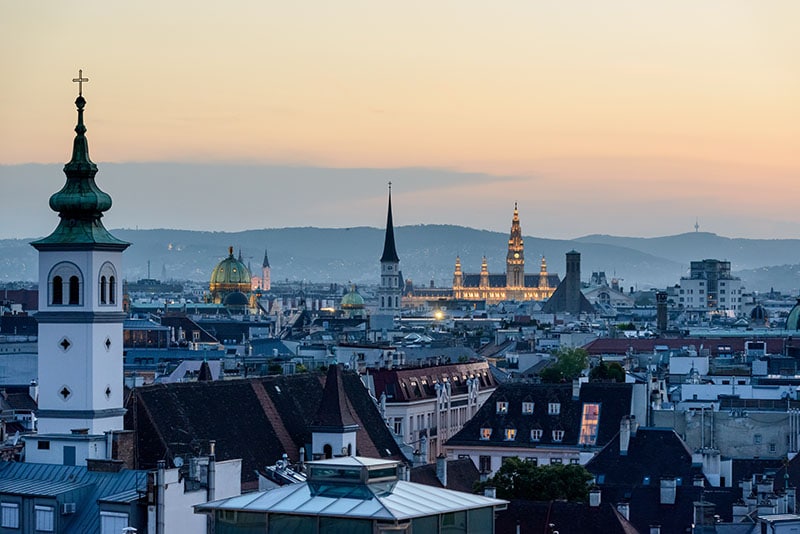 1. Panoramaansicht von Wien bei Sonnenuntergang mit historischen Kirchen und moderner Architektur, ideal für christliche Bücher, Advents- und Weihnachtsliteratur.