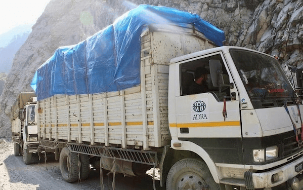 LKW mit blauer Plane auf einer Bergstraße, Transport im Gebirge, Logistik und Fracht.