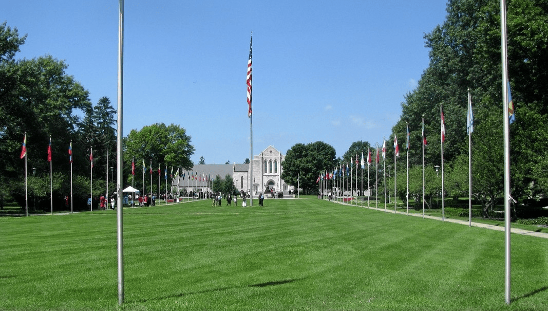 Flaggenparade vor der National Memorial Cemetery in den USA, mit grünem Rasen und blauen Himmel, symbolisiert Gedenken und nationale Identität, ideal für Artikel zu amerikanischer Geschichte und Gedenktagen.