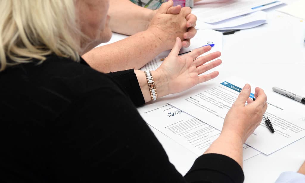 a woman sitting at a table with a paper and a pen