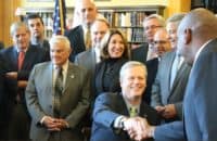 After signing bill, Massachusetts Governor Charlie Baker congratulating legislators and family members who supported the hands free driving law banning holding cell phones while driving.