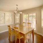 Custom shutters enhancing natural light in scenic home dining areas.