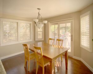 Custom shutters enhancing natural light in scenic home dining areas.