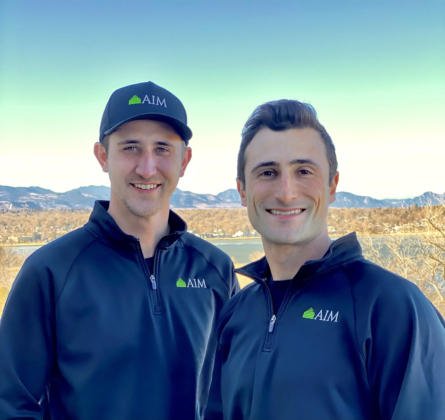 Two AIM team members in Denver wearing branded apparel outdoors.