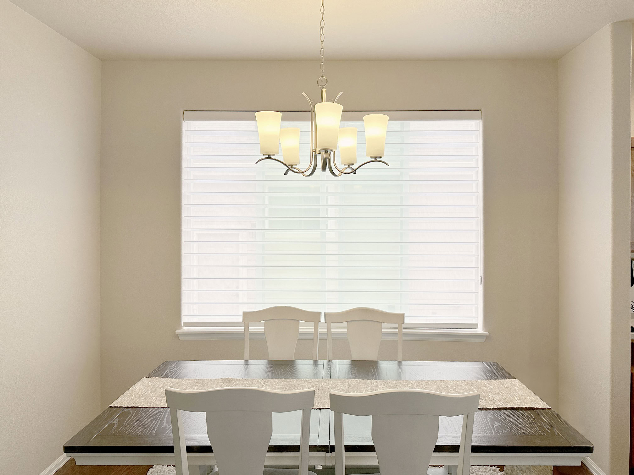 Window treatments with white blinds and elegant chandelier lighting.