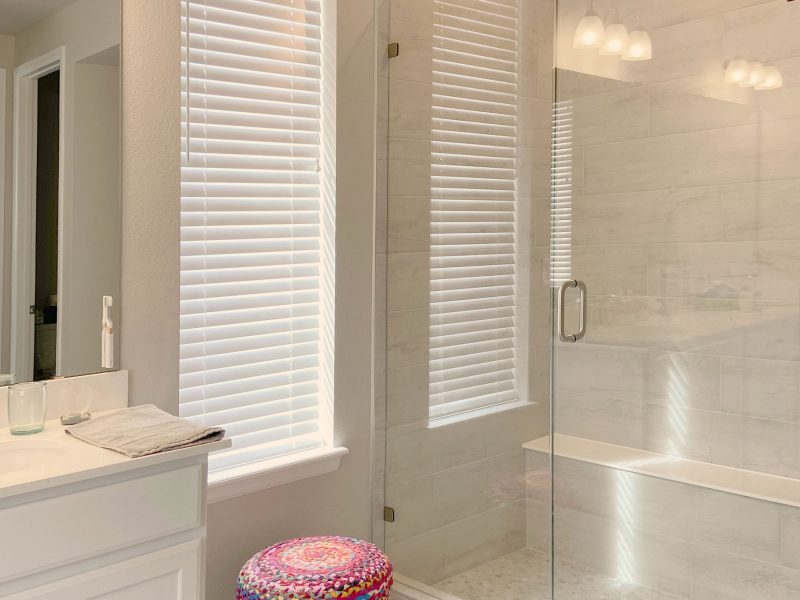 Bathroom with glass shower, white cabinets, and natural light in Fort Collins.