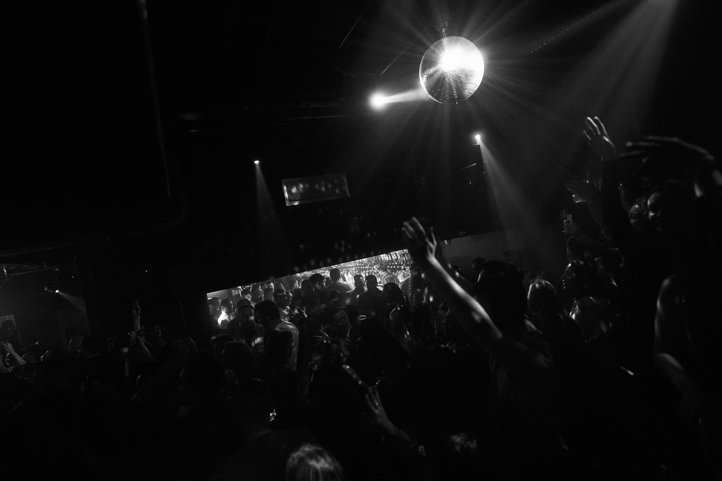 Dansen in een club met een discobal en dansers onder lichteffecten.