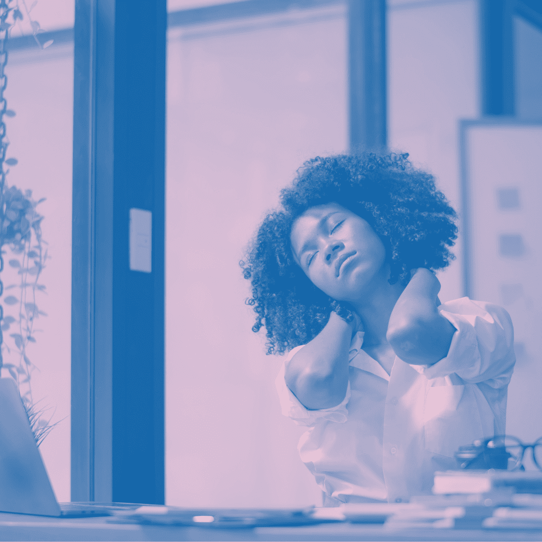 Image of woman at desk holding back of neck with eyes closed. Purple decorative tint to photo.
