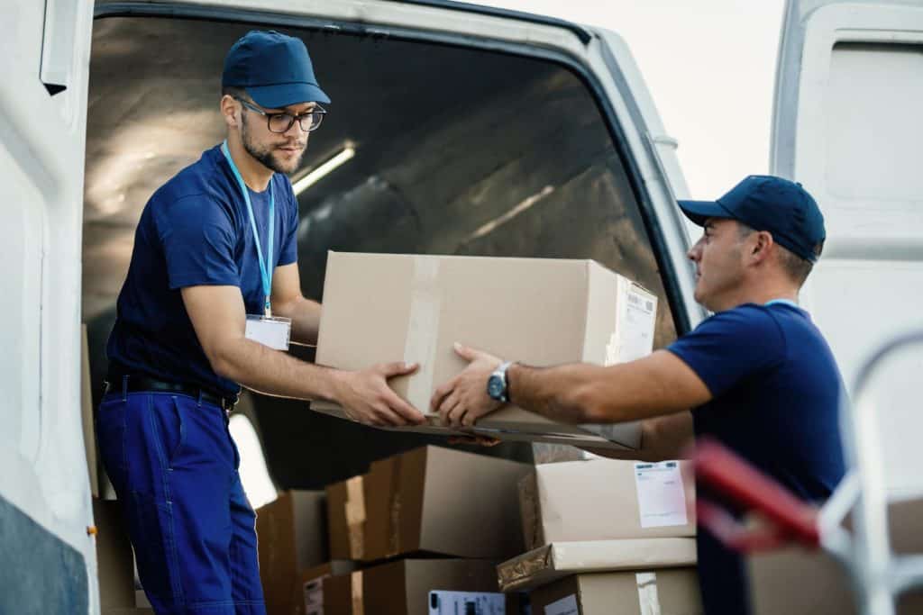 Two movers loading boxes into a moving van for local or long-distance relocation.