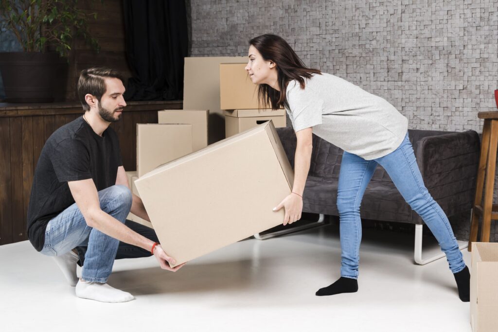 Movers in Edmonton carefully handling a large cardboard box during a move.