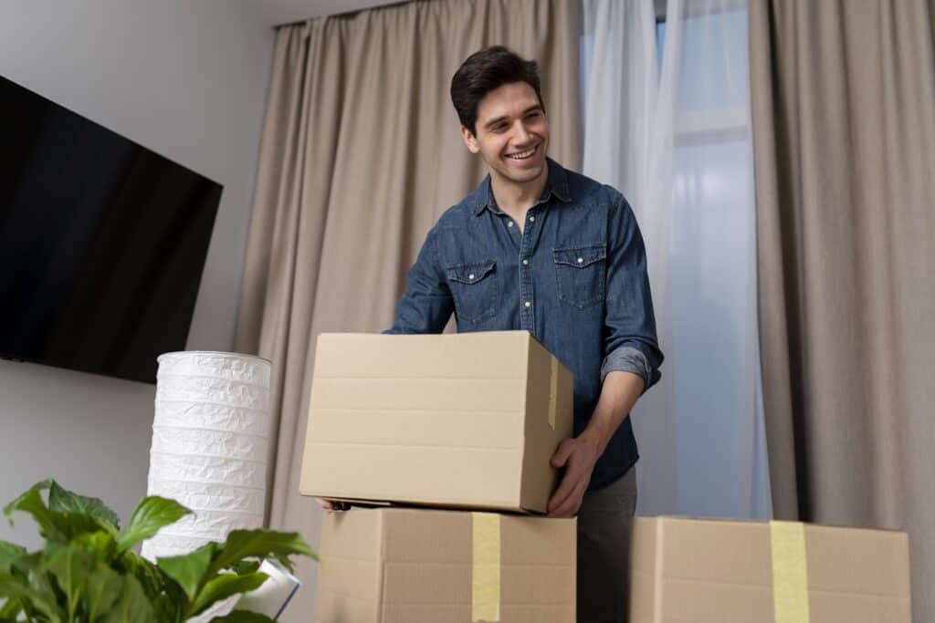 Happy man packing moving boxes in a modern living room during a move.