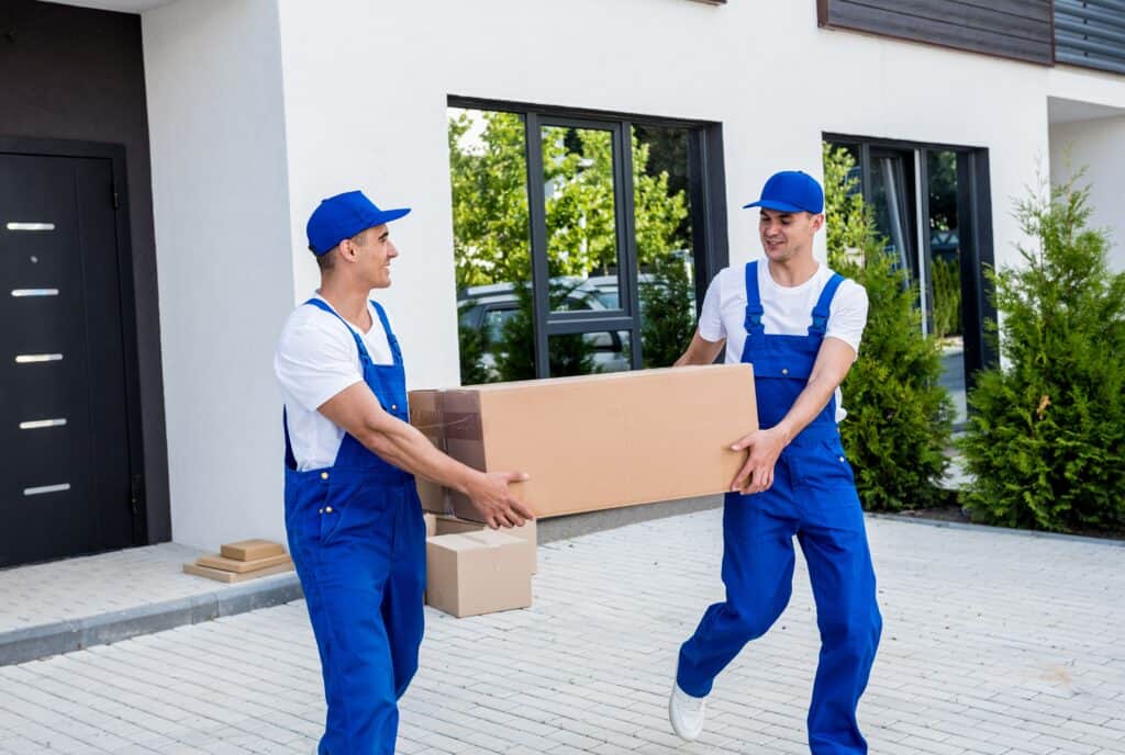 Movers in Strathmore loading a large box outside a modern house.