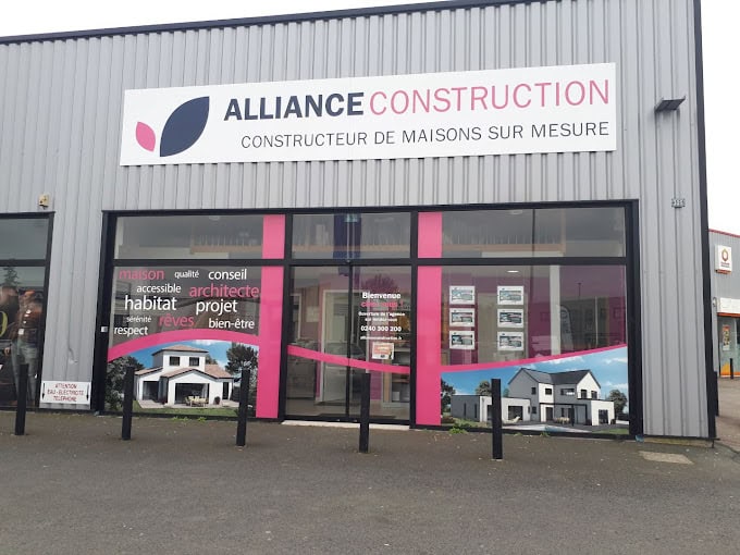 Façade d’une agence Alliance Group spécialisée dans la promotion, la construction, la rénovation et l’aménagement, avec des vitrines mettant en avant leurs réalisations et services, située dans un environnement urbain avec une entrée accueillante.