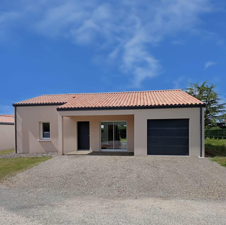 Maison de plain-pied en crépi beige avec toit en tuiles, garage intégré et grande baie vitrée, sur allée en gravier.