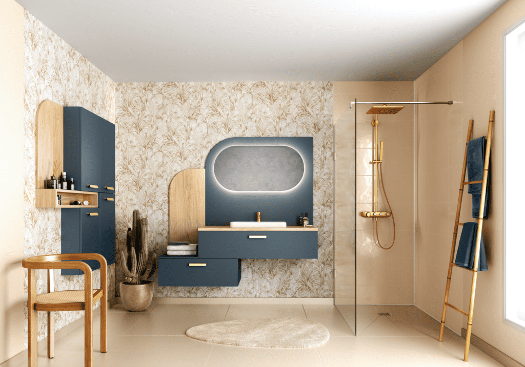 Cette salle de bain associe élégamment le bleu océan et le chêne naturel pour créer une atmosphère à la fois apaisante et sophistiquée. Le meuble suspendu, avec ses lignes asymétriques et ses poignées dorées, s'intègre harmonieusement au papier peint végétal, renforçant le style naturel et chaleureux de l'espace. La robinetterie dorée dans la douche italienne et sur le meuble lavabo apporte une touche de luxe subtil. Le miroir rétroéclairé à forme organique complète le design en ajoutant une fonctionnalité moderne et une luminosité douce. Cette pièce incarne un mélange parfait de style contemporain et d'inspiration nature.