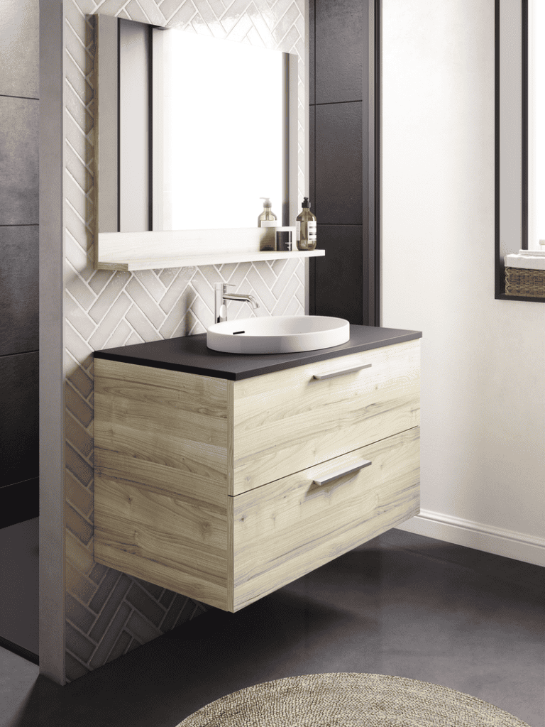 Cette salle de bain met à l'honneur un meuble suspendu en bois clair effet cerisier japonais, qui offre un design naturel et chaleureux. Le plan de travail en noir mat contraste élégamment avec le lavabo blanc ovale, ajoutant une touche contemporaine. En arrière-plan, le carrelage en chevrons beige apporte texture et caractère, tout en s'harmonisant avec l'esthétique sobre et moderne de l'ensemble. Le miroir rectangulaire avec une étagère intégrée complète ce design fonctionnel et épuré, idéal pour un espace à la fois élégant et pratique.