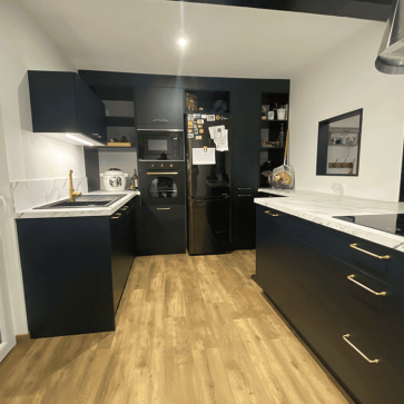 Cuisine en linéaire avec meubles noirs et plan de travail blanc.