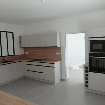 Cuisine moderne en U avec électroménagers intégrés et plan de travail en bois.