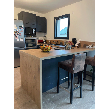 Cuisine moderne avec îlot central en bois et espace repas convivial.
