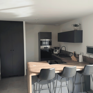 Cuisine moderne en U avec plan de travail en bois et appareils intégrés.