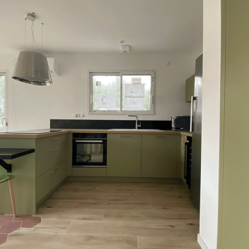 Cuisine moderne en U avec plan de travail en bois et électroménagers intégrés.