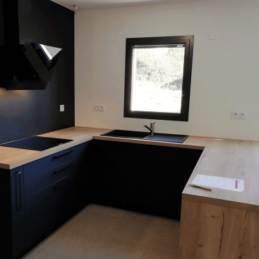 Cuisine moderne en U avec plan de travail en bois et murs noirs.