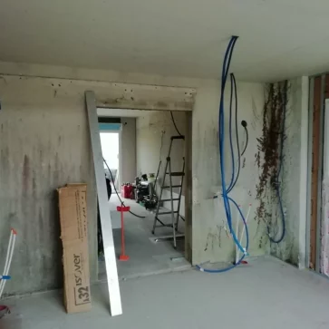 Cette pièce en cours de rénovation montre l’avancée des travaux avec la mise en place des gaines électriques et des isolants sur les murs. L’espace est préparé pour accueillir des finitions qui transformeront ce volume brut en un intérieur moderne et fonctionnel.