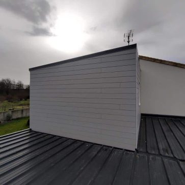 Extension de maison réalisée en bardage gris, posée sur une toiture en bac acier. La finition soignée du revêtement et l’intégration harmonieuse de l’extension témoignent d’un travail de rénovation moderne et durable.