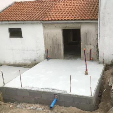 Voici une étape clé dans la transformation de cet espace extérieur : la mise en place de la dalle en béton, préparée pour accueillir une nouvelle construction. Ce socle robuste intègre les raccordements nécessaires, assurant une base solide pour le projet à venir, tout en respectant les contraintes du bâti existant.
