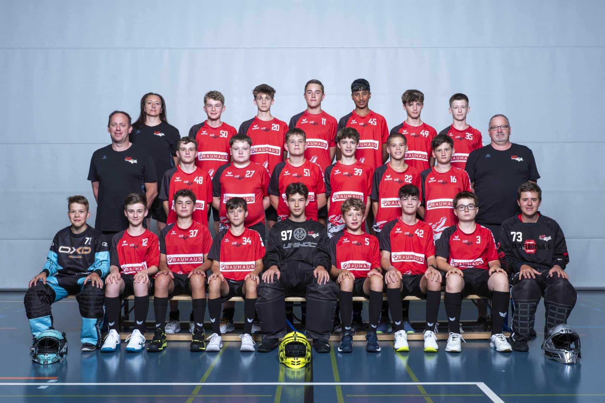 Gruppenbild des UHC Alligator Malans Nachwuchsteams in Sportbekleidung vor grauem Hintergrund.