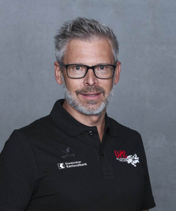 UHC Alligator Malans Trainer im schwarzen Polo mit Vereinslogo und Brille, professionelles Portrait.