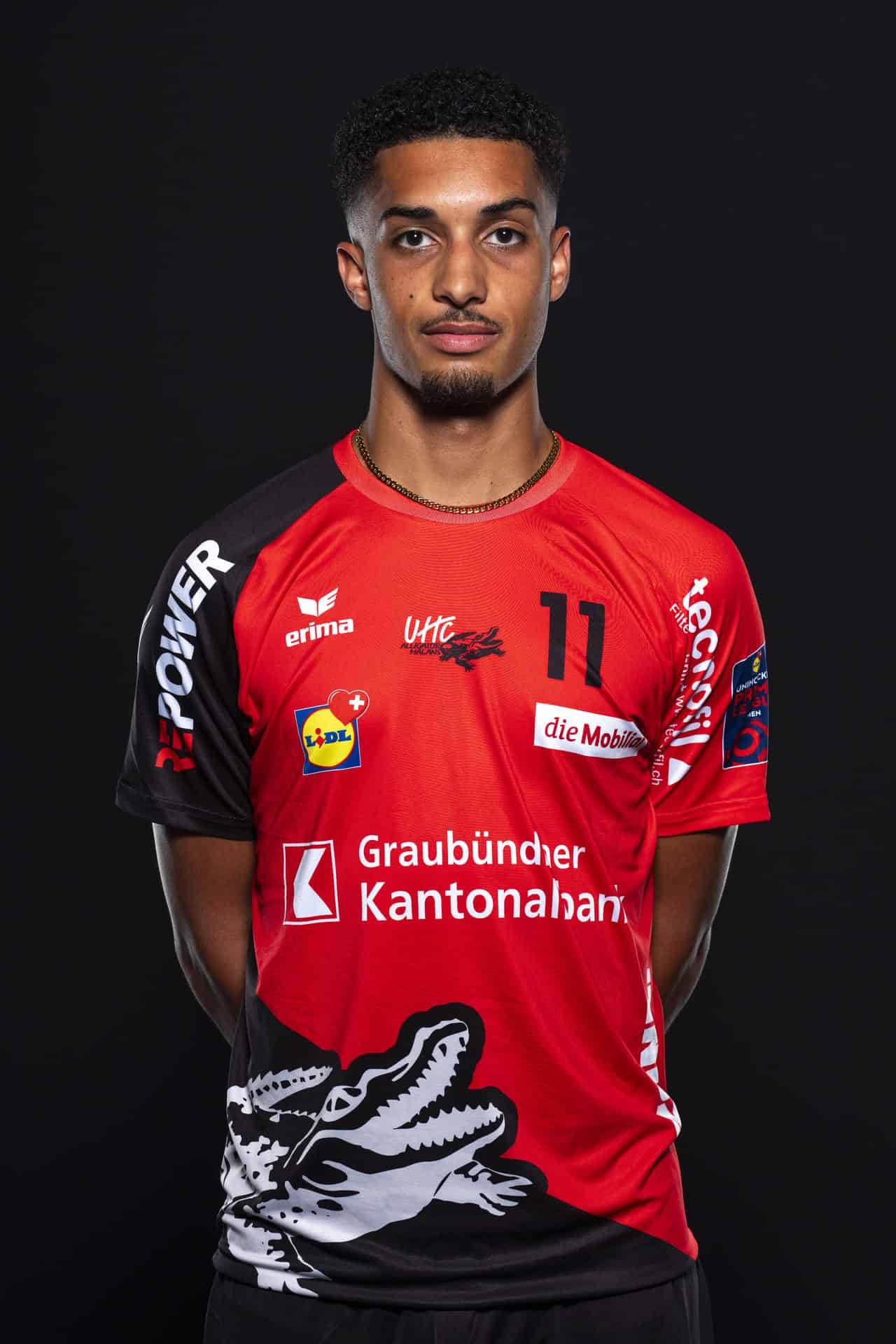 UHC Alligator Malans Volleyballspieler in Teamtrikot mit Logo, Sponsoren und Nummer 11, professioneller Auftritt, Schwarz Hintergrund, Sport, Mannschaft, Spiel.