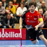 Dynamischer UHC Alligator Malans Unihockeyspieler beim Spiel, begeistertes Publikum im Hintergrund, Indoor-Sportveranstaltung, Mannschaftsgeist, actionreiche Szene, Sportevent in der Schweiz.