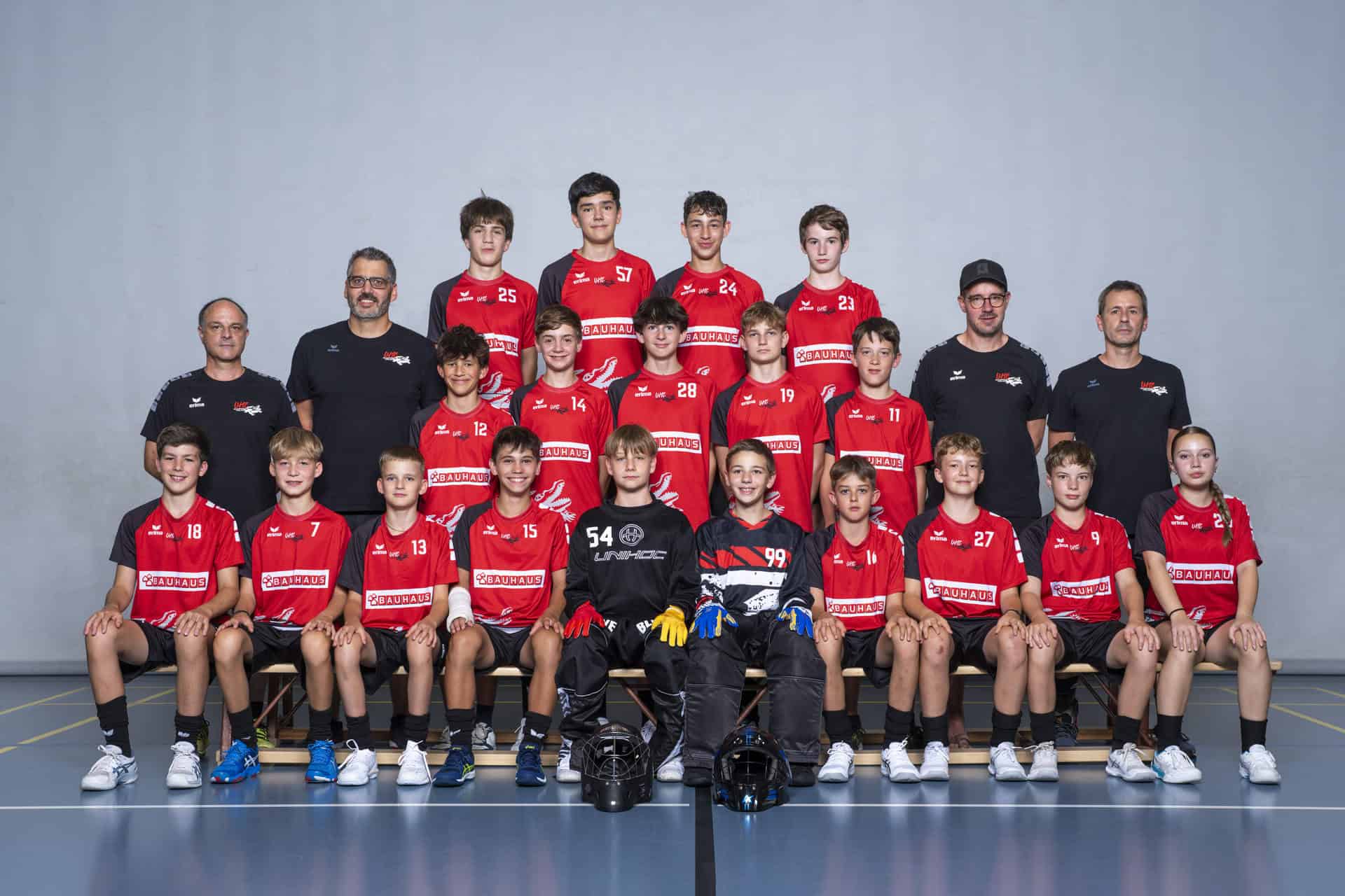 UHC Alligator Malans Jugendmannschaft im Handball mit Trainern vor neutralem grauem Hintergrund.