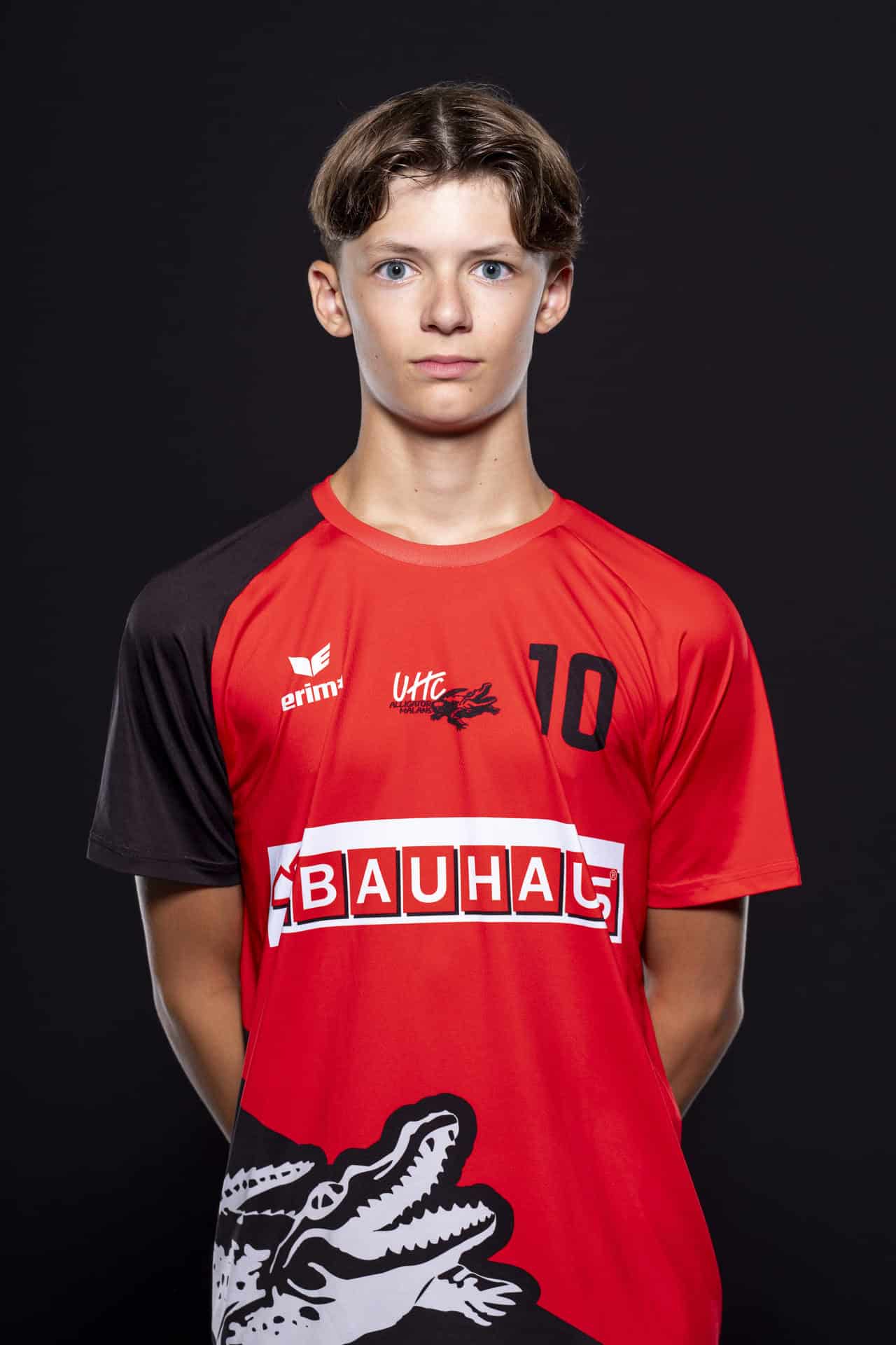 Junge Volleyballspielerin im roten Trikot mit der Nummer 10, UHC Alligator Malans, auf schwarzem Hintergrund, sportliche Mannschaftssportart, Team Malans Volleyball, Jugendmannschaft, sportliche Betätigung, Teamgeist, Volleyballspieler.