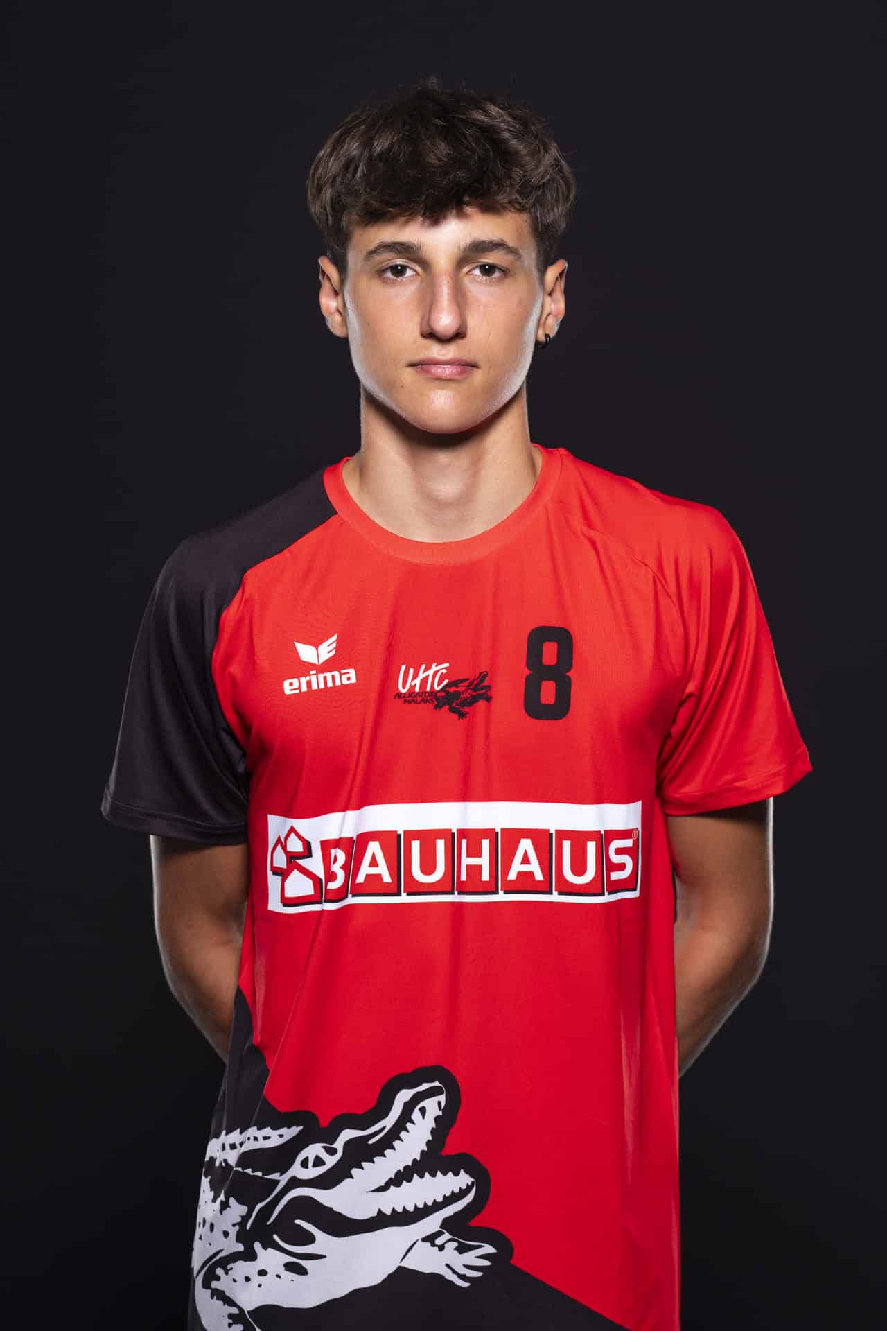 Herrenhandballspieler des UHC Alligator Malans in rotem Trikot mit schwarzem Branding, auf dunklem Hintergrund, mit Fokus auf Sportler, Team und Handball.