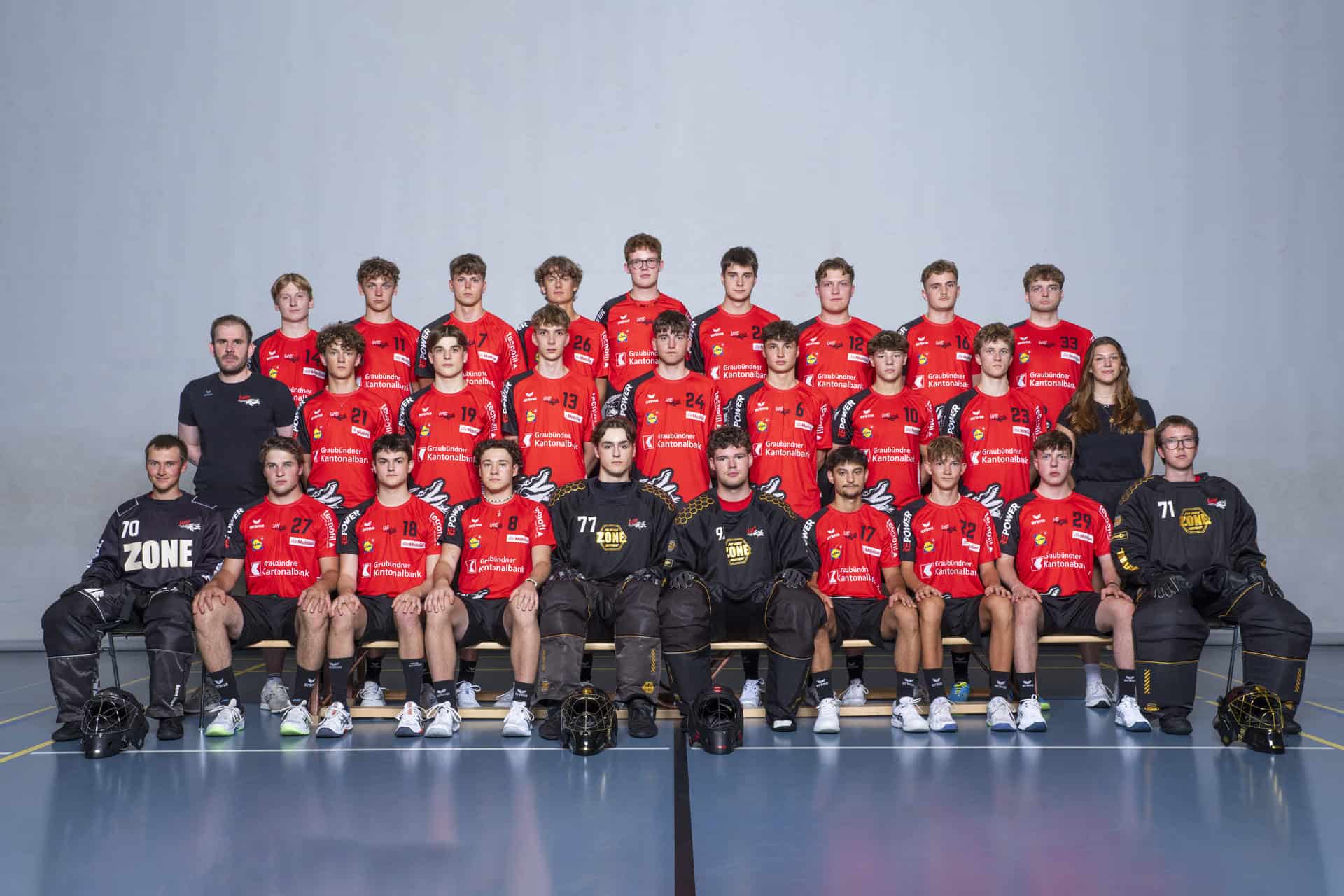 Teamfoto UHC Alligator Malans, Eishockeymannschaft in roten Trikots, mit Trainer und Torhütern, indoor, sportliches Mannschaftsporträt für die Webseite.