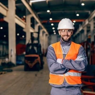 Ingeniero con casco y chaleco de seguridad en planta industrial moderna.