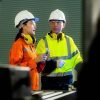 Dos ingenieros en seguridad eléctrica revisando equipo en planta industrial.