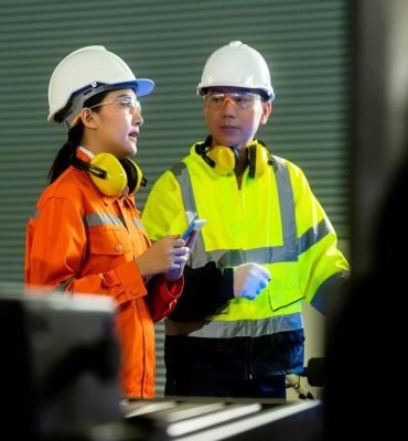 Dos ingenieros en seguridad eléctrica revisando equipo en planta industrial.