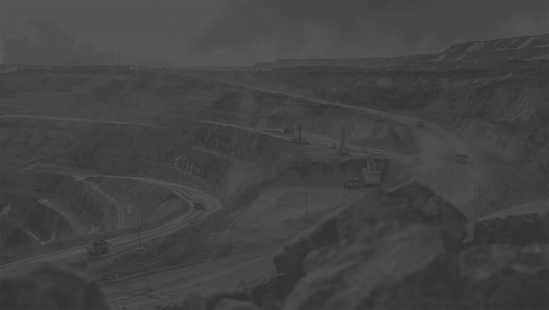 Height of an open pit mine with mining, heavy machinery and rocky terrain.
