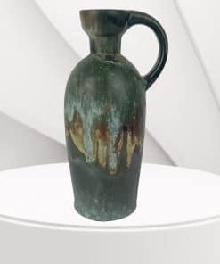 1960s Ruscha Vase 321 with handle, featuring earthy green, brown and red drip glaze, studio pottery style, approx. 20cm tall, displayed on a white curved surface.